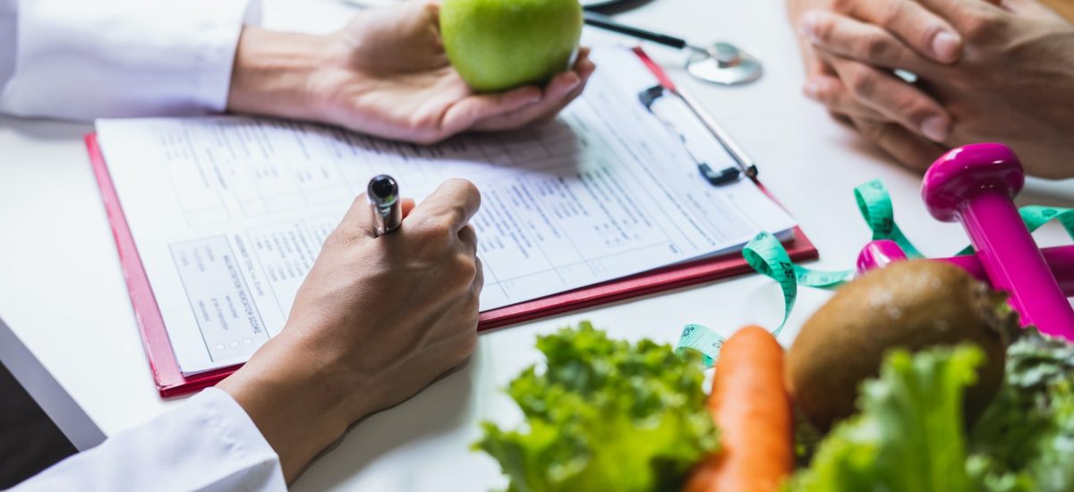 Nutritionist giving consultation to patient with healthy fruit and vegetable